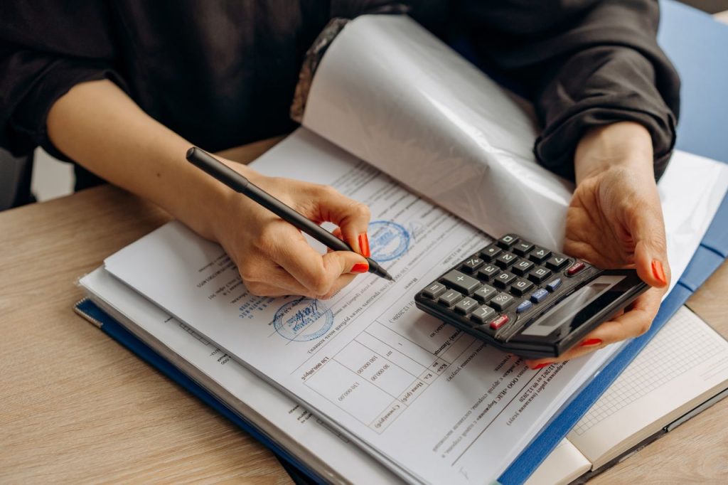 WorkSafeBC Reporting An bookkeeper using a calculator and signing paperwork, showcasing financial analysis.