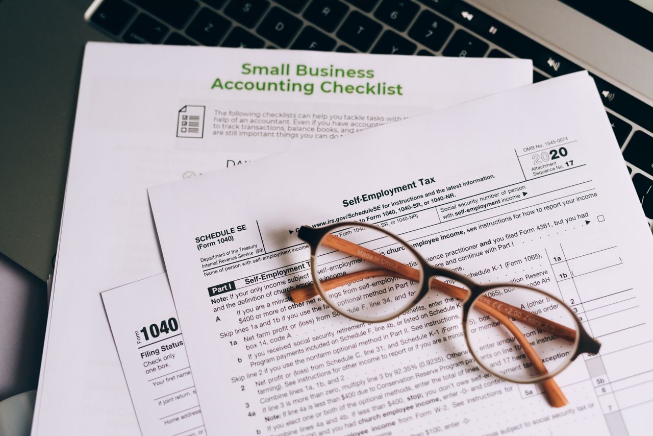 why-choose-us Close-up of tax forms and a small business accounting checklist on a laptop.
